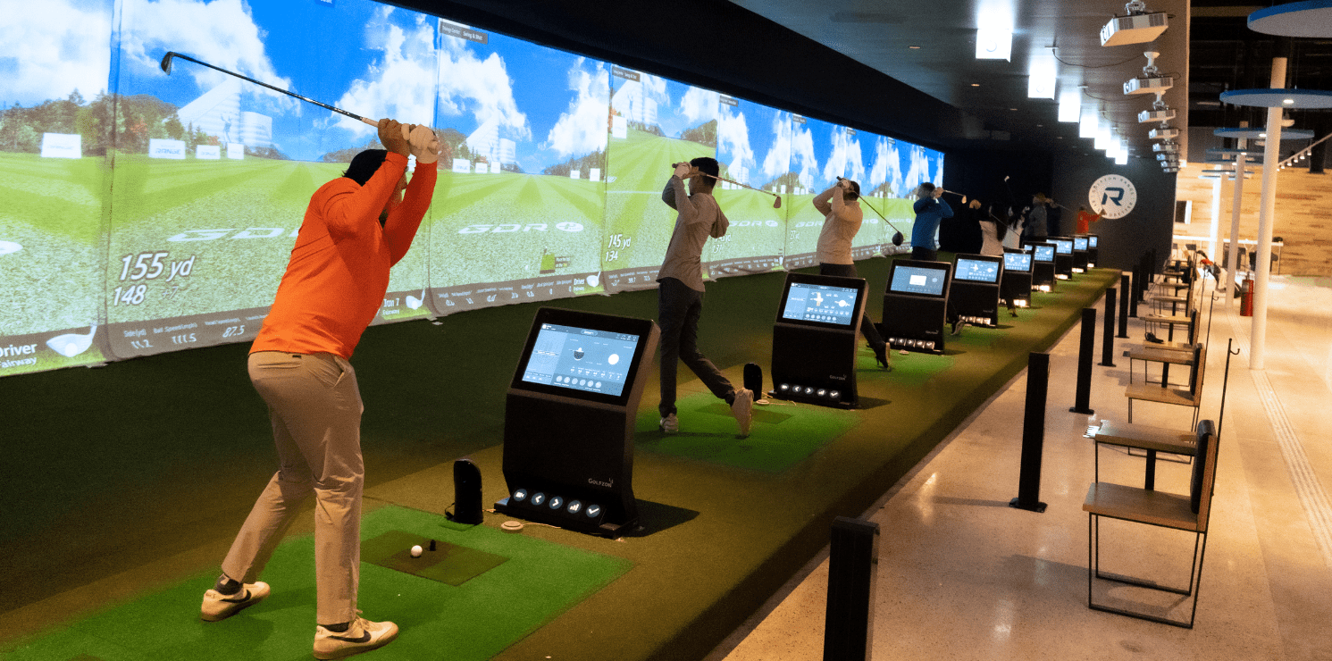 blog-fig-1 Commercial golf simulator facility with multiple simulator bays and immersive virtual golf technology
